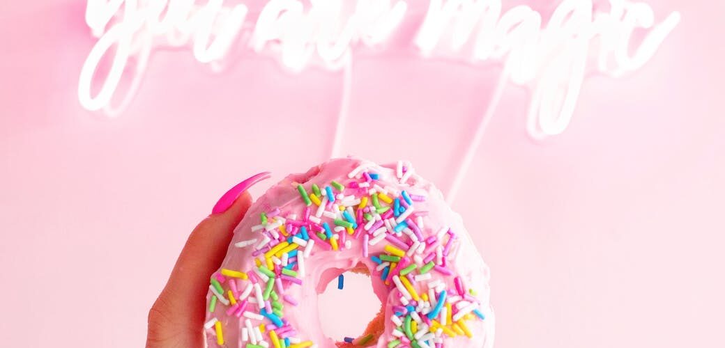 woman holding donut with sprinkles