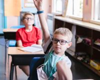 boy raising his hand in the classroom